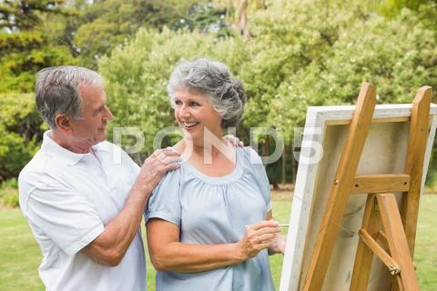 Happy retired woman painting on canvas with husband Stock Photos