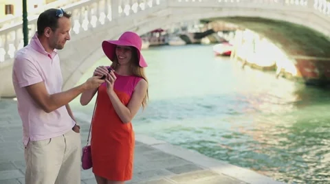 Happy rich couple standing with cellphone on the street in Venice Stock Footage