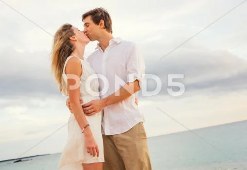 Happy romantic couple kissing on the beach at sunset, man and woman in love Stock-Fotos