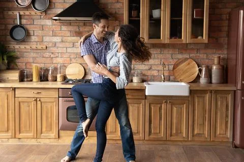 Happy romantic young couple dancing in renovated kitchen. Stock Photos