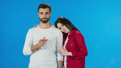 Happy romantic young couple drinking red wine, on blue background. Stock Footage 140600937