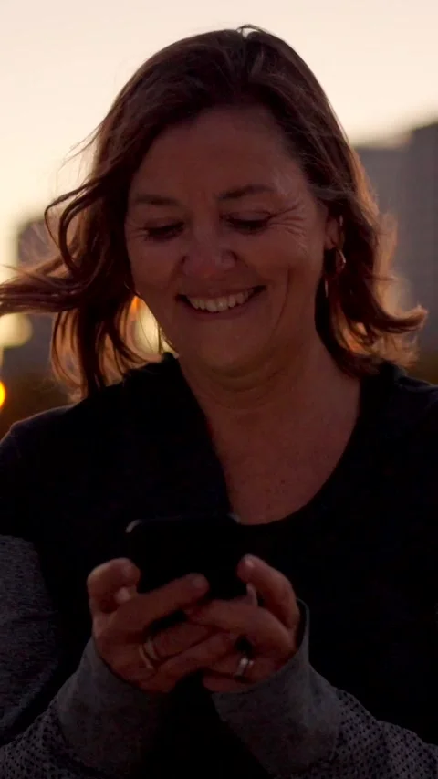 Happy runner using phone during sunset after exercising Stock Footage 259757865