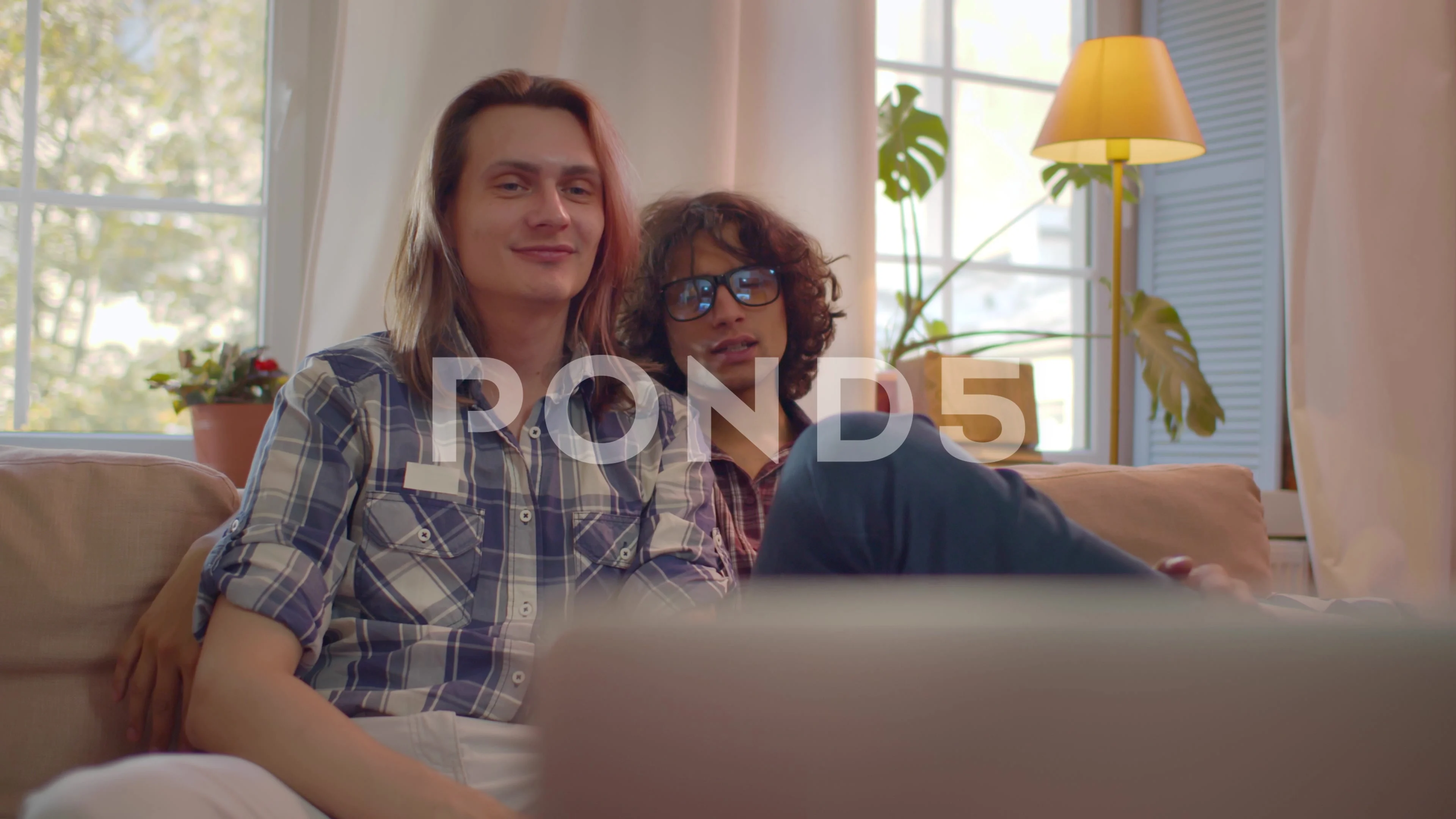 Happy same-sex male couple having video chat with friends on laptop.  Realtime