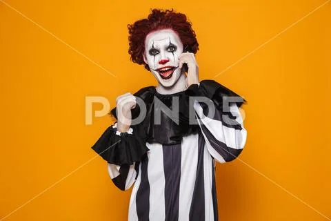 Happy scary clown talking on smartphone isolated Stock Photos
