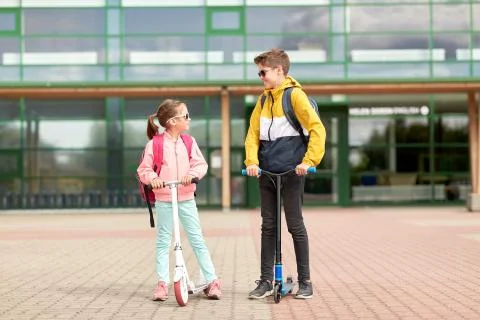 Happy school children with backpacks and scooters Stock Photos