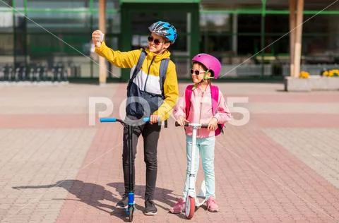 Happy school kids with scooters taking selfie Stock Photos