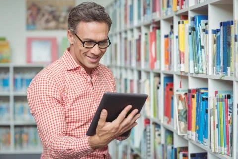 Happy school teacher using digital tablet in library Stock Photos