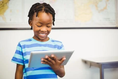 Happy schoolboy using digital tablet in classroom 스톡 사진
