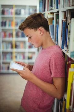 Happy schoolboy using digital tablet in library Stock Photos