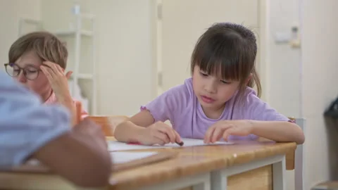 Happy schoolgirl smiling while drawing in classroom Stock Footage 339377306