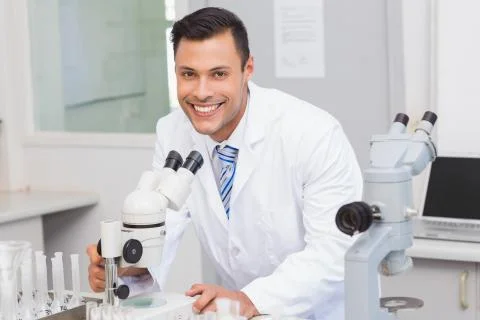 Happy scientist using microscope 스톡 사진