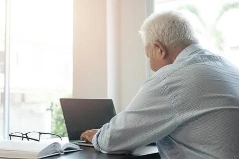 Happy senior Asian using the laptop for calculating and make a note of daily  Stock Photos