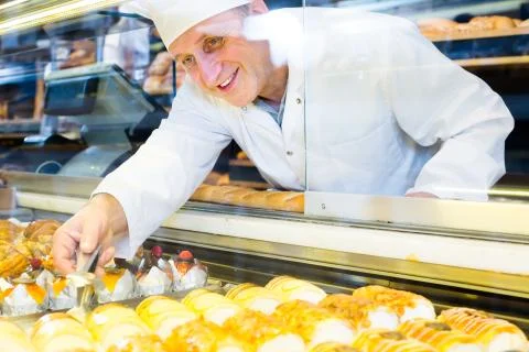 Happy senior baker with sweet cakes in local confectionery Stock Photos