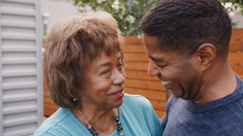 Happy senior black woman and her middle aged son embracing, head and shoulders, Stock Footage