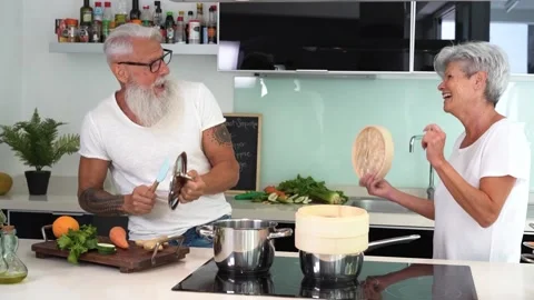 Happy senior couple dancing while cooking together at home Video stock 137440668