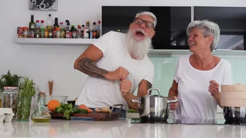 Happy senior couple dancing while cooking together at home Stock Footage 137440678