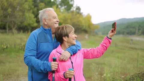 Happy senior couple doing video call trekking in the woods - Healthy elderly and Stock Footage
