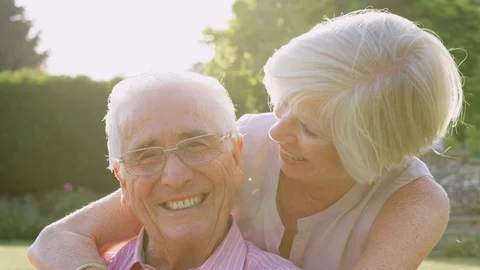 Happy senior couple embrace and smile to camera in garden Stock Footage