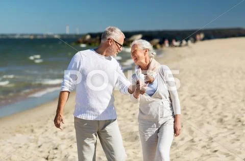 Happy senior couple holding hands on summer beach Stock Photos