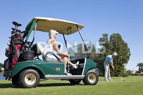 Happy senior couple playing golf with cart Stock Photos