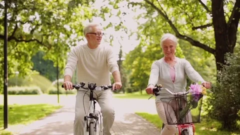 Happy senior couple riding bicycles at summer park Stock Footage