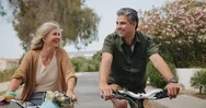 Happy Senior Couple Riding Bikes In Suburban Street In Spring Stock Footage