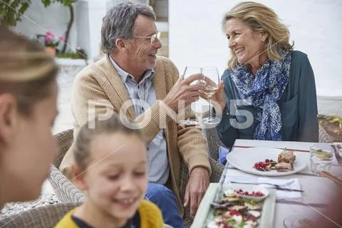 Happy senior couple toasting white wine glasses at patio lunch Stock Photos