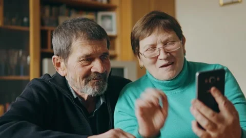 Happy senior couple using mobile phone together for video call to talk Stock Footage 243125436