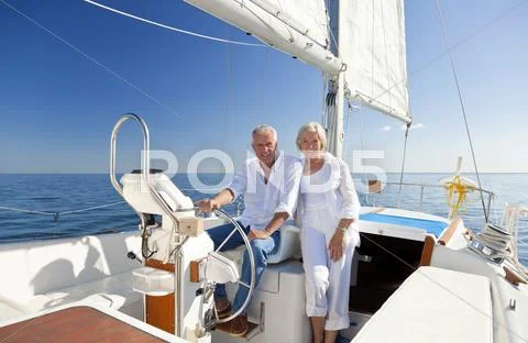 Happy senior couple at the wheel of a sail boat Stock Photos