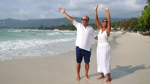 Happy Senior Couple in White Clothes on Vacation at Beach Stock Footage 73930833