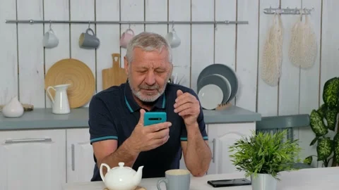 Happy senior elderly beared man holding smart phone, video calling online Stock Footage 146332636