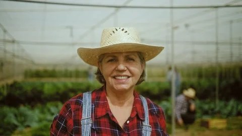 Happy senior farmer smiling at the camera while working inside greenhouse Stock Footage 238562830