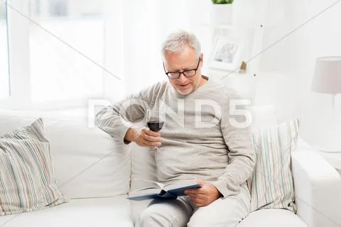 Happy senior man drinking wine and reading book Stock Photos