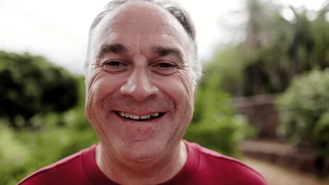 Happy senior man looking at camera outdoors with Park Nature in background Stock Footage 255138666
