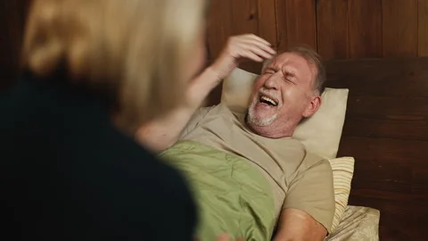 Happy senior man lying in bed laughing and talking with his caring wife Video stock 329752663