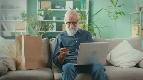 Happy Senior Man Using Laptop Computer for Paying for Shopping with Credit Card Stockbeeldmateriaal 196247321