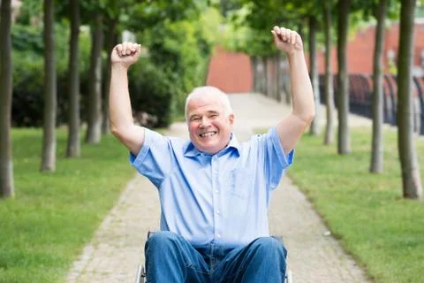 Happy Senior Man On Wheelchair With Arm Raised Stock Photos