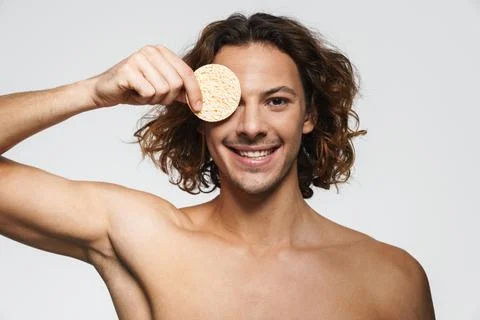 Happy shirtless guy smiling while posing with cosmetic sponge Stock Photos