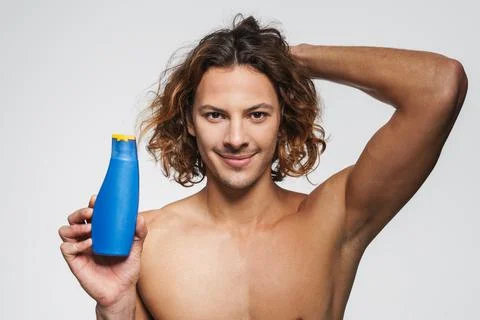 Happy shirtless guy smiling while posing with shampoo Stock Photos