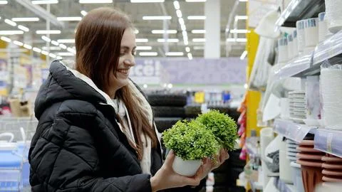 Happy shopper browsing small artificial potted plants in the gardening aisle of Stock Photos