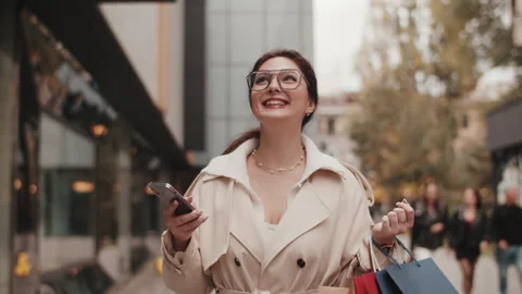 Happy shopper using navigation app walking down city street Stock Footage 289561994