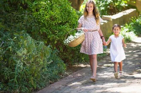 Happy siblings walking holding hands in garden Stock Photos