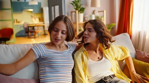 Happy sisters falling sofa enjoying soft pillows fabric closeup. Smiling couple Stock Footage 333339065
