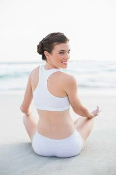 Happy slim brown haired model in white sportswear meditating in lotus position Stock Photos