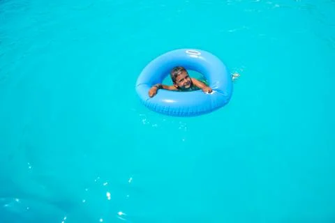 Happy small boy in inflatable ring swimming alone Stock Photos