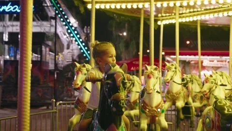 Happy small boy riding carousel at park, kid enjoying summer night seated on top Stock Footage 253514368
