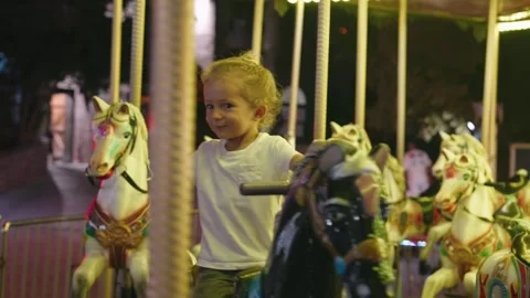 Happy small boy riding carousel at park, kid enjoying summer night seated on top Stock Footage 253849251