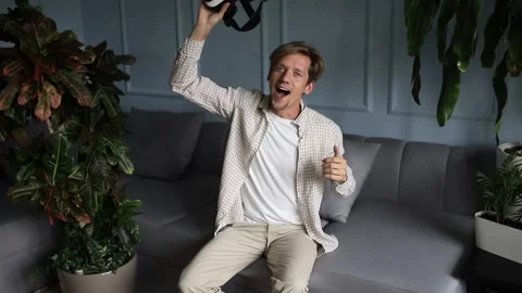 Happy smiley young man taking off vr glasses releasing from 3d reality Stock Footage 241017713