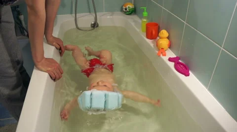 Happy smiling 4-month old baby learning to swim on his own in the tub special Stock Footage 62155117