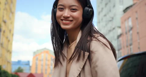 Happy Smiling Asian Girl in Headphones walking at the street. Looking into Stock Footage